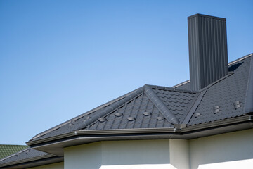 Obraz premium Grey corrugated metal profile roof installed on a modern house. The roof of corrugated sheet. Roofing of metal profile wavy shape. Modern roof made of metal. Metal roofing.