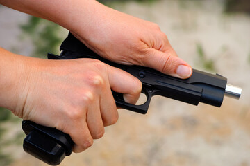 A person racking the slide of an airsoft gun.