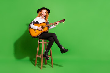 Full length body size view of attractive cheerful girl sitting on chair playing guitar isolated...