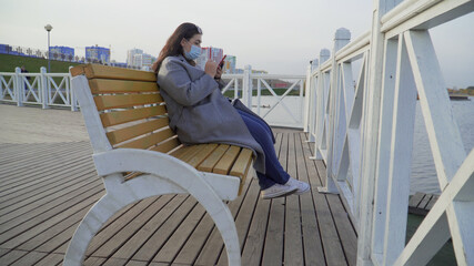 A young woman with a phone in her hands wearing a mask