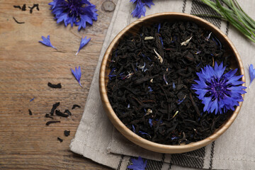 Obraz na płótnie Canvas Dried cornflower tea and fresh flowers on wooden table, above view