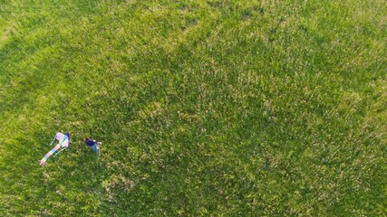 Aerial top view footage of running female while she flying a colorful kite on the high grass meadow in the mountain fields. Outdoor time spending concept 4K footage. 