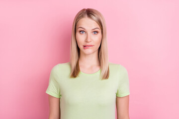 Obraz premium Photo of girlish nervous stupid blonde lady bite lip make mistake wear green t-shirt isolated on pink background