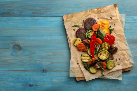 Delicious grilled vegetables on light blue wooden table, top view. Space for text