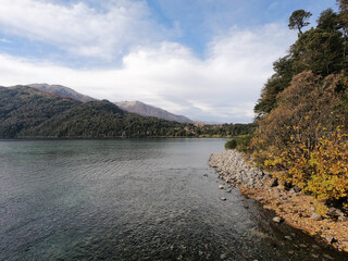 Fototapeta premium Lake Falkner in a sunny autumn day. View of the pure water, Andes mountains, shoreline and forest in San Martín de los Andes, Patagonia, Argentina. 
