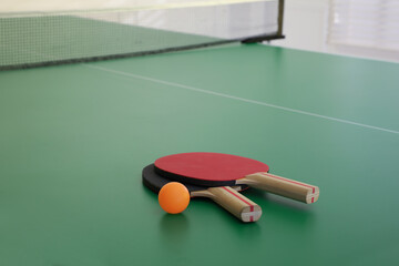 Rackets and ball on ping pong table, space for text