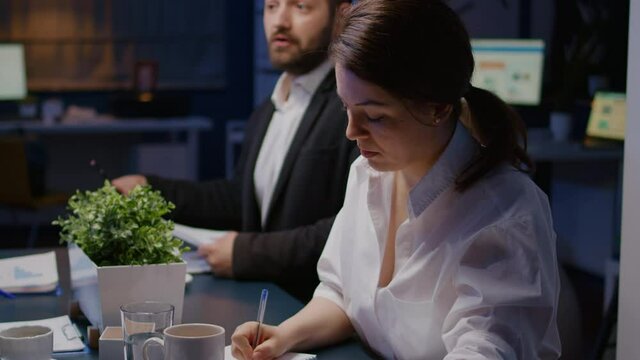 Portrait of smiling businesswoman looking into camera working overtime in business company meeting office room late at night. Workaholics diverse multi-ethnic teamwork discussing investment strategy