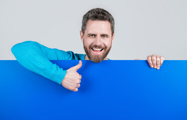 product presenting. presenting novelty information. male behind blue paper show thumb up.