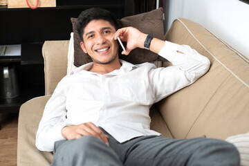 Obraz premium Latino man talking on the mobile phone lying on the sofa at home
