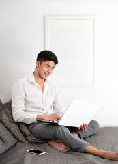 Latino man working in bed with laptop