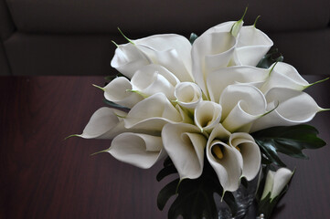 bridal bouquet of white calla lilies side view on a brown background closeup. Selective focus