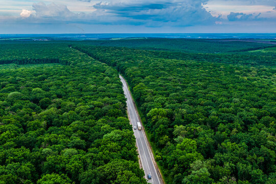 white truck driving on asphalt road through a green forest. Drone top view. Aerial view landscape. © drotik
