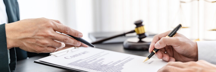 Lawyer preparing to sign a contract and wooden gavel on table justice and law concept.