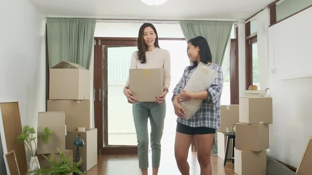 Happy asian women LGBT lesbian couple holding boxes entering new modern house.family unpacking boxes.