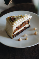 Piece of carrot homemade cake with white cream on a white plate