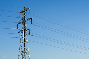 Electricity pylon tower with cables over blue sky landscape