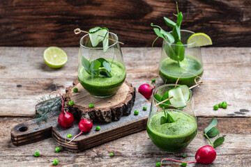 Blended green smoothie with ingredients on wooden table. Detox smoothie, green fresh peas, cucumber, radish, spinach and lime. banner, menu recipe place for text, top view