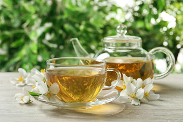 Obraz na płótnie Canvas Aromatic jasmine tea and fresh flowers on wooden table