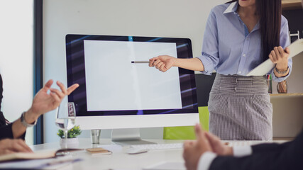 Close up of team business people sitting at office meeting presentation discussion pointing at a laptop computer  blank white screen at the office. Mock up.