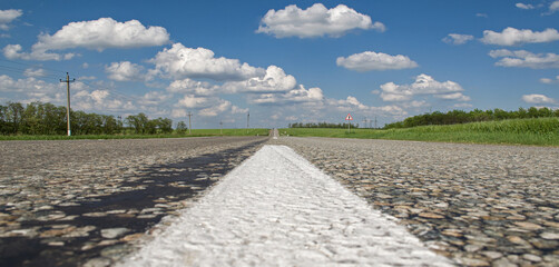 the road leading into the distance clouds and fields