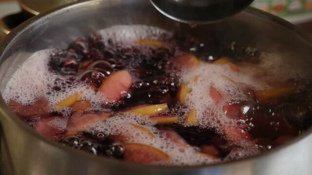 Cooking compot. beverage made of variety of fresh berries. Boiling water in saucepan mixing and stirring with ladle. Slow motion. Refreshing drink with bubbles, foam. Making delicious homemade compote