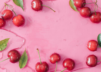 Fresh cherry fruits and leaves in water. Creative food background with copy space. Minimal nature border.