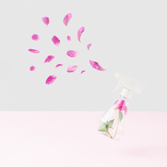 Pink peony flower in spray bottle and petals against pastel pink and bright gray background. Minimal floral scent concept. Creative love nature idea.