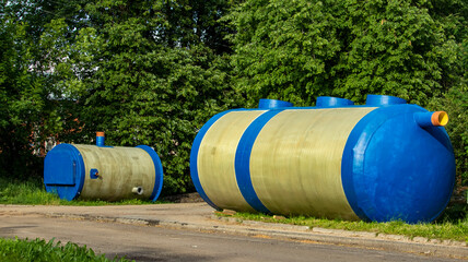 two huge blue containers for collecting wastewater on the grass