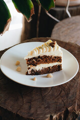 Piece of carrot homemade cake with white cream on a white plate