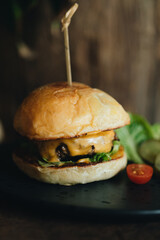 Fresh tasty burger on old dark wooden table