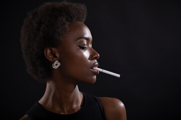 Sexy african american woman smoking cigarette on black background.
