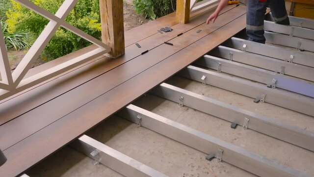 Flooring installation work builder construction terrace. Renovation house. Deck plank in terrace. Wood floor covering. Repair home deck floor of wood panels connecting. Laying floorboards on a terrace