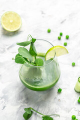 Fresh green smoothie Healthy Detox Drink with green leaves of kale green fresh peas, cucumber, spinach and lime on white background