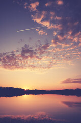Scenic golden sunset over calm water, color toning applied.