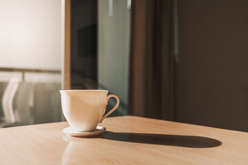 Hot cup of drink on the table in sun light of calm and warm morning.