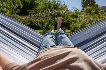 Point of view of woman lying in hammock in the garden enjoying good weather. Focus on background.