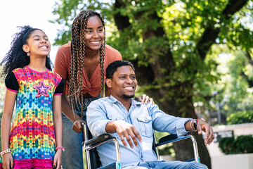 Man in a wheelchair enjoying a walk outdoors with family.