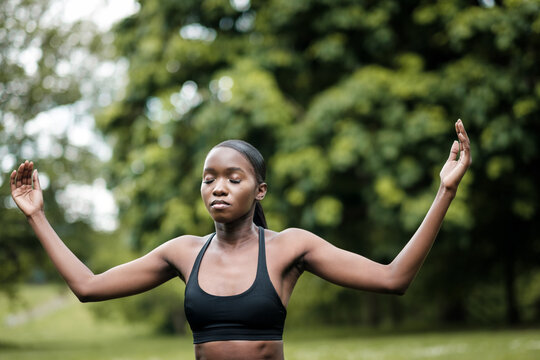 Young black woman doing meditation and yoga in a park.