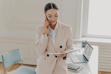 Smiling businesswoman talking on phone and consulting client
