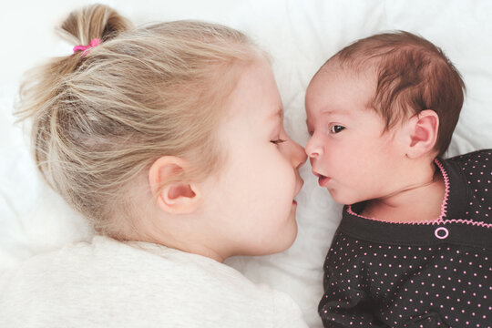 Big sister and baby sister eskimo kissing
