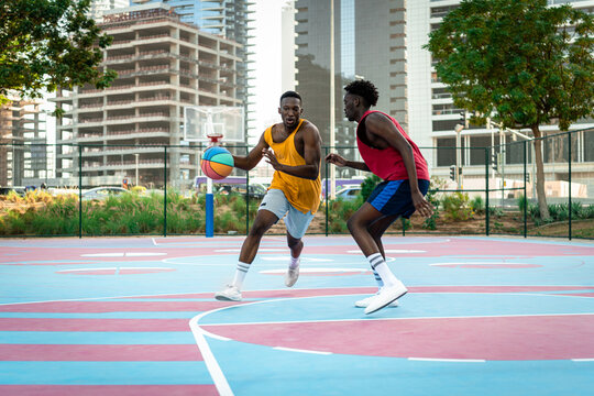 Two young African American men playing basketball.