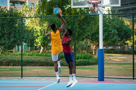 Two young African American men playing basketball.