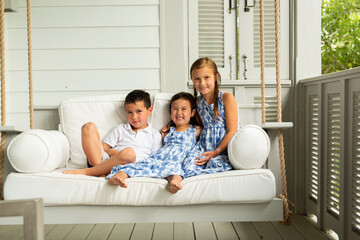 Little Brother and Sisters Sitting on Porch Swing
