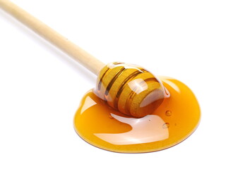 Honey dripping from wooden dipper and creating puddle isolated on white background