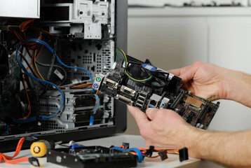 A technician is holding the motherboard in a desktop case.