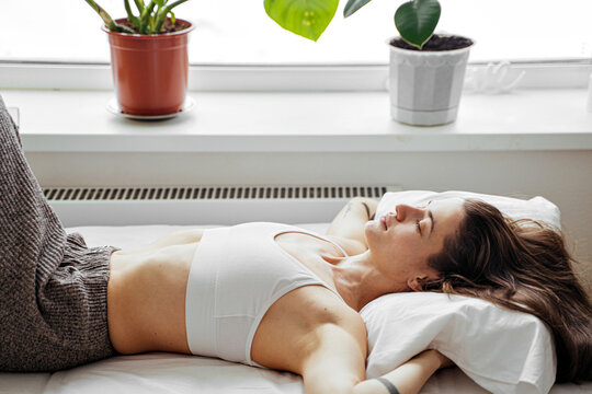 young female resting on the bed by the window