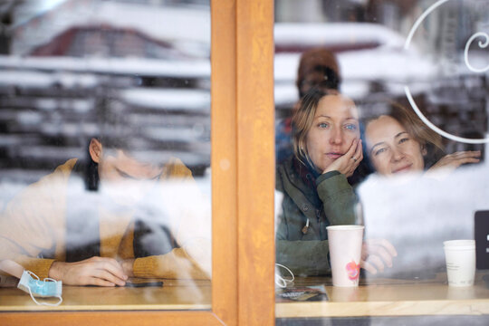Through glass friends sitting at table in cafeteria