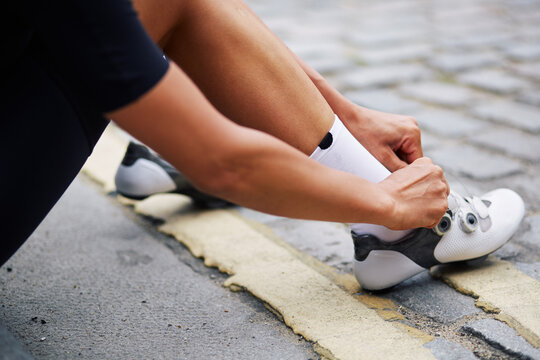 Cycling female athlete cyclist adjusts bike socks before entering road race
