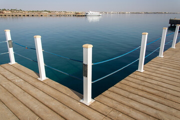 Naklejka premium Travel. Pier on the sea. View at the sea from the wooden pier with posts and ropes with sparkling sea water