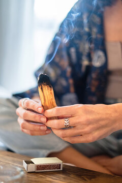 Woman burning palo santo wood at home